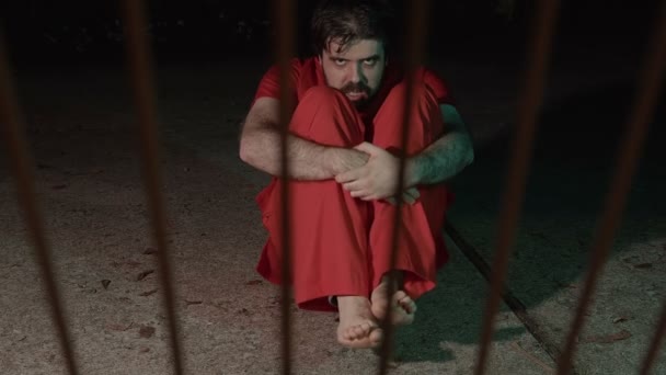 Un prisonnier effrayant en colère qui regarde dans les barreaux de prison - Séquence, vidéo