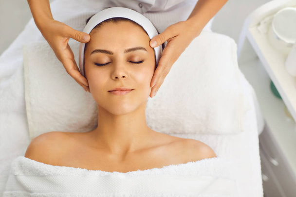 Female face massage in a beauty salon. Beautician makes facial skin treatment in a beauty clinic - Фото, изображение