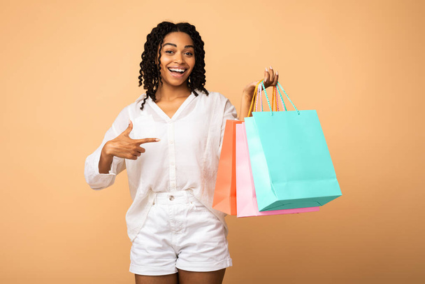 Happy Customer Pointing Finger At Shopper Bags Over Beige Background - Photo, Image
