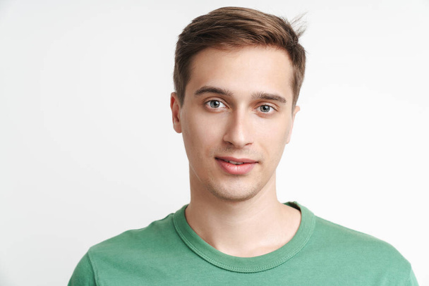 Image of young caucasian man in basic t-shirt looking at camera isolated over white background - Foto, imagen