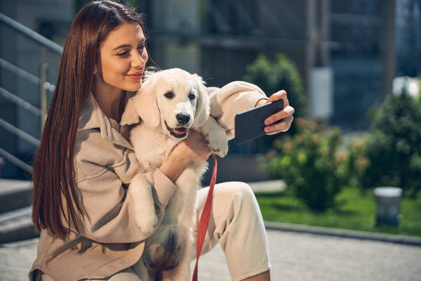 Sorridente signora fotografarsi con il suo cane al di fuori - Foto, immagini