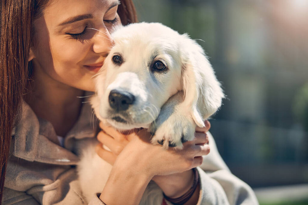 Glückliche hübsche Dame umarmt ihr Haustier im Freien - Foto, Bild
