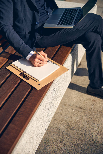 Man in suit writing in document outside - 写真・画像