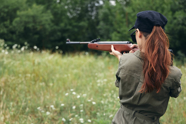 女性の上の自然銃で手で狩りバックビューブラックキャップ緑の木  - 写真・画像