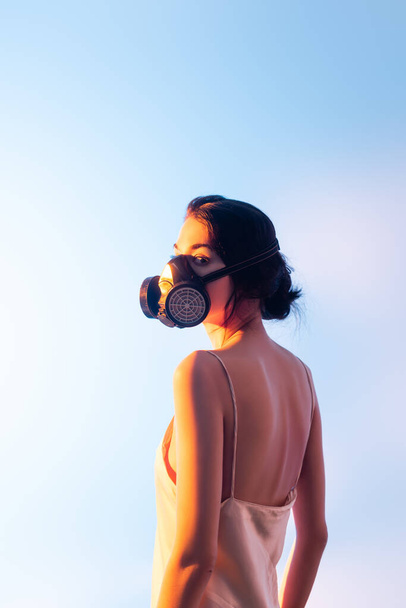brunette woman in gas mask standing on blue - Fotografie, Obrázek