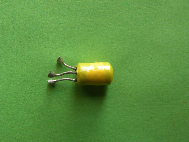Κίτρινο χρώμα Capacitor ηλεκτρονικό συστατικό σε πράσινο φόντο - Φωτογραφία, εικόνα