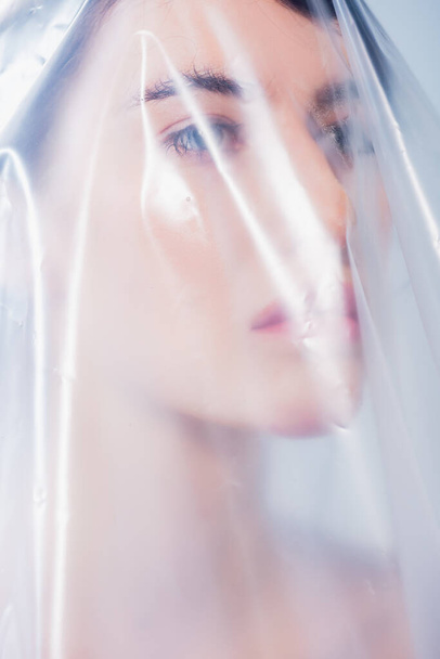 woman covered with polyethylene looking away, ecology concept - Photo, Image