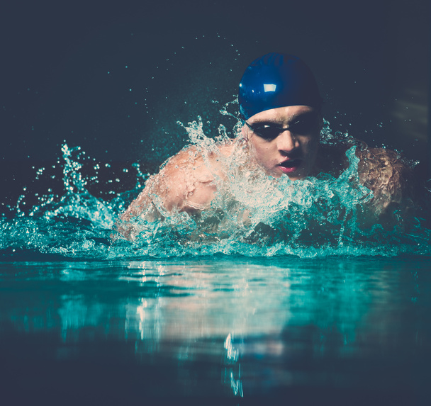 mięśni młody człowiek w niebieską czapkę w basenie - Zdjęcie, obraz
