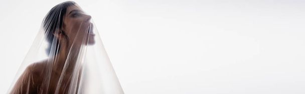immagine orizzontale di donna bruna urlando attraverso polietilene isolato su bianco, concetto di ecologia - Foto, immagini