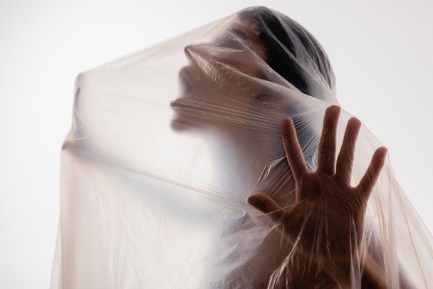 femme effrayée criant à travers le polyéthylène isolé sur blanc, concept d'écologie - Photo, image