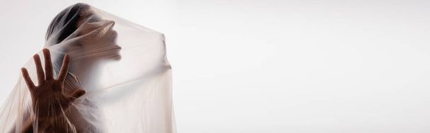 Panoramaaufnahme einer brünetten Frau, die durch Polyethylen schreit, isoliert auf Weiß, ökologisches Konzept - Foto, Bild