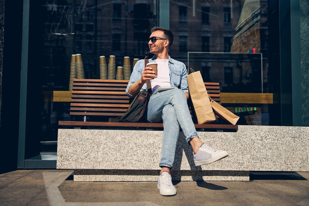 Hombre relajado cruzando las piernas mientras está sentado en el banco - Foto, imagen