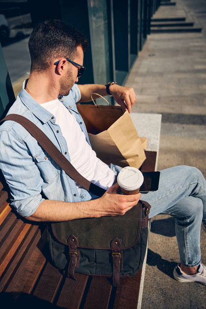 Attente brunette man op zoek in zijn papieren zak - Foto, afbeelding