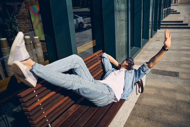Relajado joven hombre acostado en el banco - Foto, Imagen