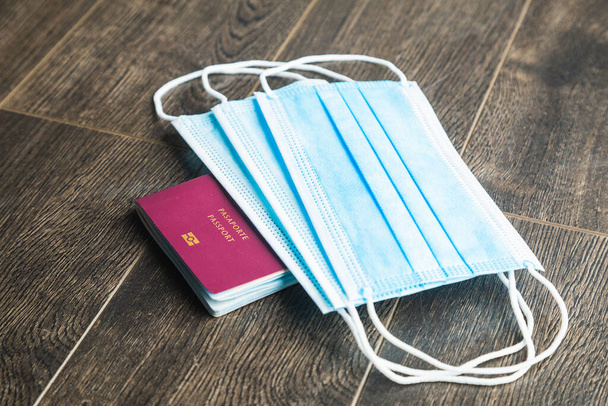 a top view of a red passport and world above some blue masks - Photo, Image