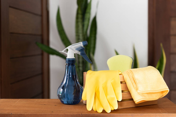 Basket of cleaning supplies on  wood table in house with green Sanseviera laurentii plant background - Fotó, kép