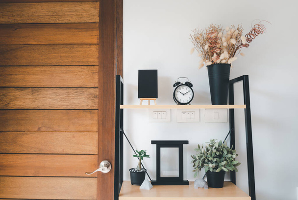 Wooden shelf with bouquet of dry flower,grass in pot, greenery in vase, alarm,photo frame and black board  over white wall  decoration in living room at home - Foto, immagini