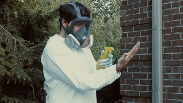 Человек распыляет руку во время пандемии с СИЗ снаряжением на улице - Кадры, видео