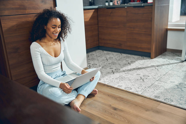 Tyytyväinen paljain jaloin tumma tukka nainen käyttää hänen laptop - Valokuva, kuva