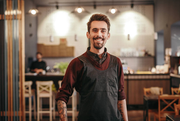Smiling male bartender in modern cafe - Foto, imagen