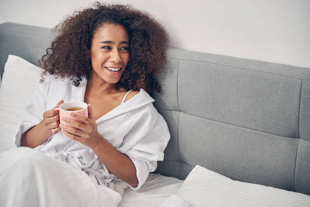 Cheerful African American woman sitting in bed - Photo, Image
