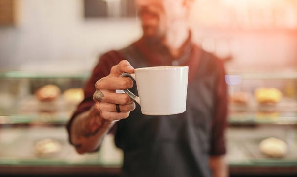Barista serving cup of hot coffee - Фото, зображення