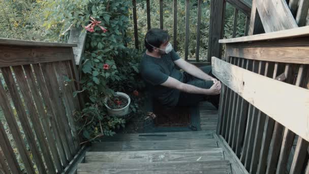 Hombre sentado alrededor durante la pandemia con una mascarilla en el exterior - Imágenes, Vídeo