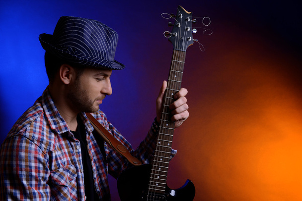 Young musician playing guitar on dark color background - Foto, afbeelding