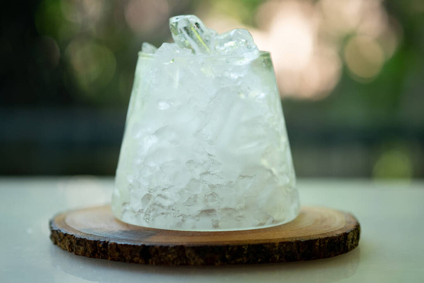 Sklenice ledu na stole v přírodně zeleném pozadí - Fotografie, Obrázek