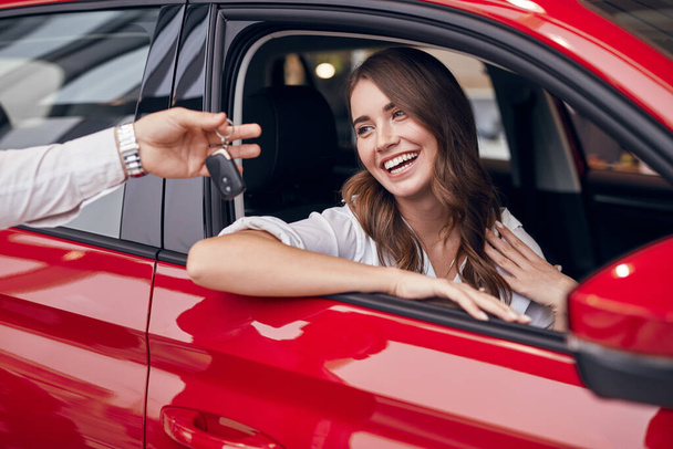 Happy young woman getting keys of new car - Фото, зображення