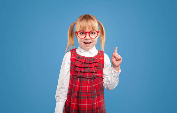 Smart schoolgirl in eyeglasses pointing up - Fotoğraf, Görsel