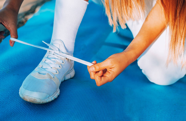 спортивна дівчина прив'язує мережива на кросівки перед тренуванням
 - Фото, зображення
