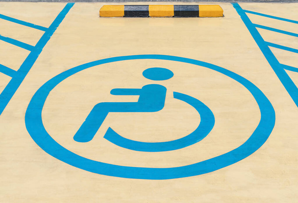Vammaisten pysäköintiopasteet parkkipaikan lattialla, Vammaisten pysäköintiopasteet ostoskeskuksen konseptissa, Pyörätuolin symbolissa istuvan henkilön grafiikka harmaalla maalla parkkipaikoilla. - Valokuva, kuva