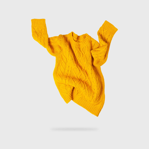 Sárga narancs repülő nők őszi kötött pulóver világosszürke háttérrel. Kreatív ruházat koncepció, trendi ősz téli hangulatos pulóver pulóver mez. Női divat, őszi kedvezmények. Vásárlás. - Fotó, kép