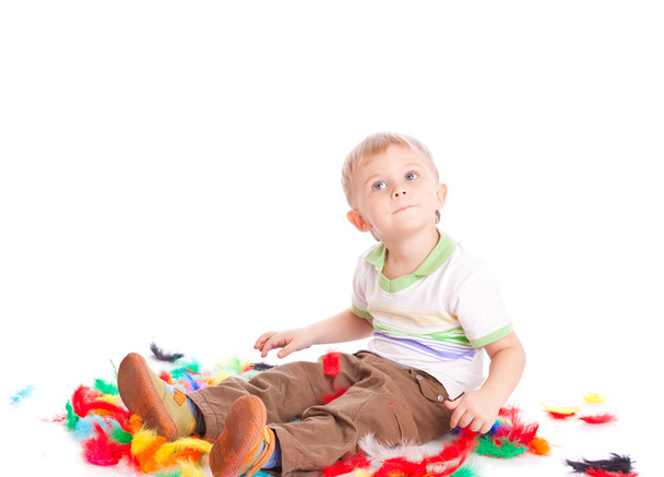 Little boy is sitting on a flow with feathers - Фото, зображення