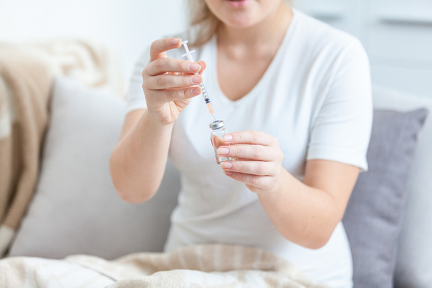 Photo of woman lying in bed and filling syringe with medicines - Photo, Image