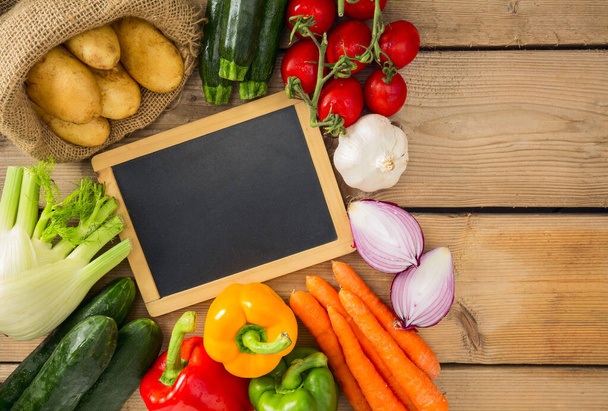 Black Chalk Board  with Assorted Organic Veggies on Sides on Top of Wooden Table. - Photo, Image
