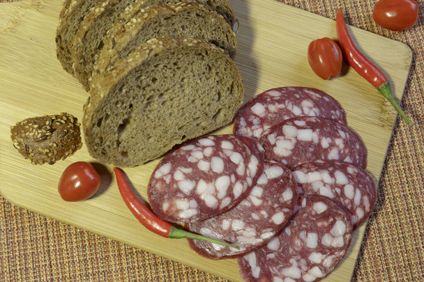 Salami sausage and bread for sandwiches, sliced on cutting board. - Photo, Image