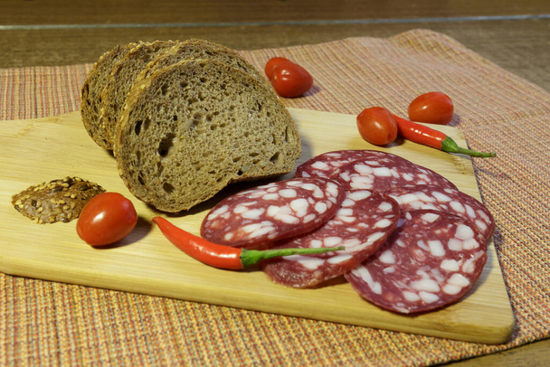 Salsiccia di salame e pane per panini, affettati sul tagliere. - Foto, immagini