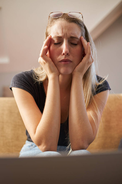 Стресс молодая женщина работает из дома на диване в гостиной - Фото, изображение