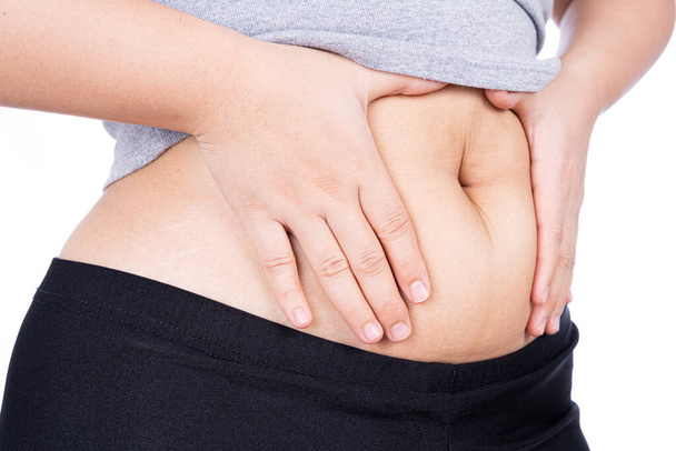 Tlustá žena drží nadměrné tlusté břicho, tlusté břicho izolované přes bílé pozadí. Dietní životní styl, hubnutí, žaludeční svaly, zdravý koncept. - Fotografie, Obrázek