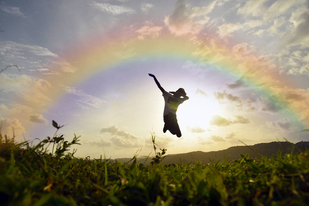 счастливый прыжок маленького мальчика против радуги и заката . - Фото, изображение