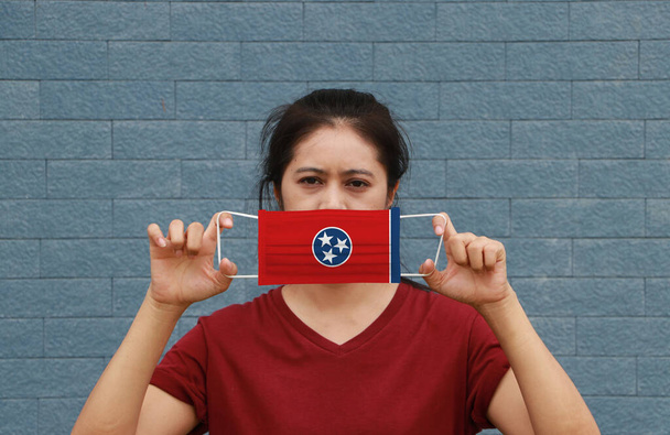 Nainen ja hygieeninen naamio Tennessee lippu kuvio kädessään ja nostaa sen peittämään kasvonsa. Maski on erittäin hyvä suoja Tiny Particle tai virus corona tai Covid 19. - Valokuva, kuva