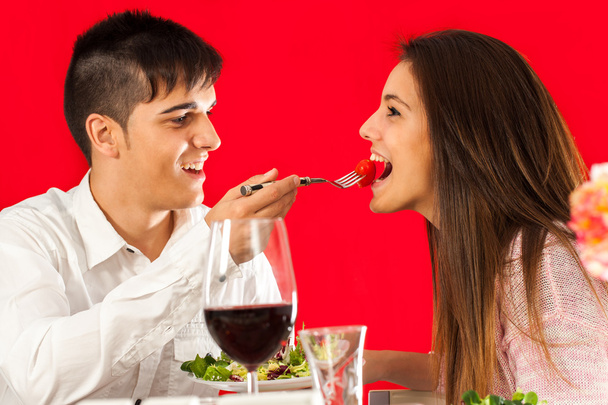 Boy feeding girlfriend at dinner table. - Photo, Image