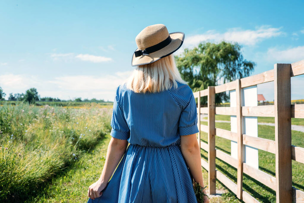 Cottagecore Farmcore Countrycore aesthetics, fresh air, countryside, slow life, pastoral life, outdoor picnics, wearing grandma clothes. Young girl in straw hat with flowers walks on country farm. - Photo, Image