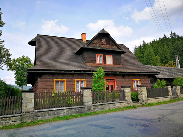 Cottage volledig gebouwd van hout, met houten hek, staan bij de asfaltweg, afbeelding - Foto, afbeelding