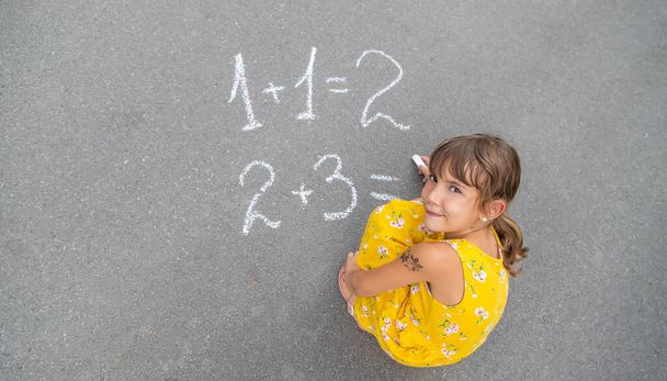 A criança escreve matemática no pavimento. Foco seletivo. Verão. - Foto, Imagem