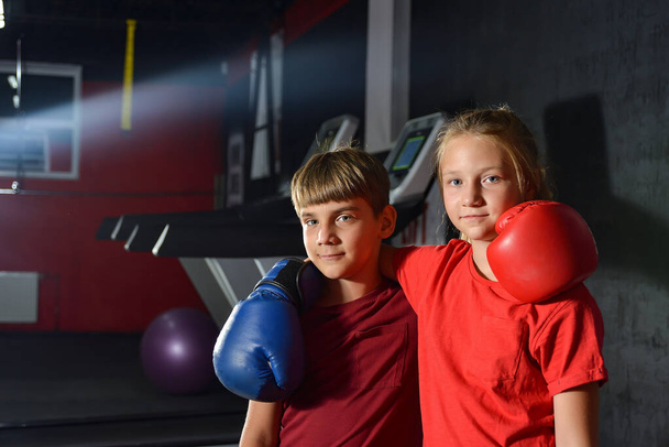 Брат и сестра в боксёрских перчатках обнимаются. Дети занимаются боксом. - Фото, изображение