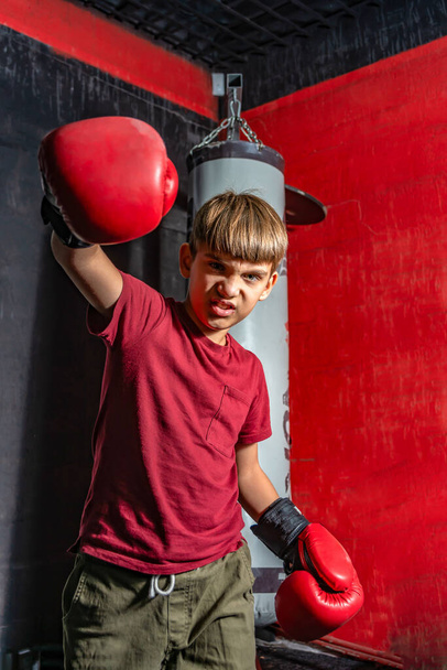 Egy tinédzser fiú bokszkesztyűben dühösen üti az öklét egy ütésért.. - Fotó, kép