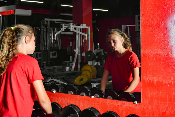 Cansada adolescente se mira en el espejo después de entrenar. - Foto, imagen